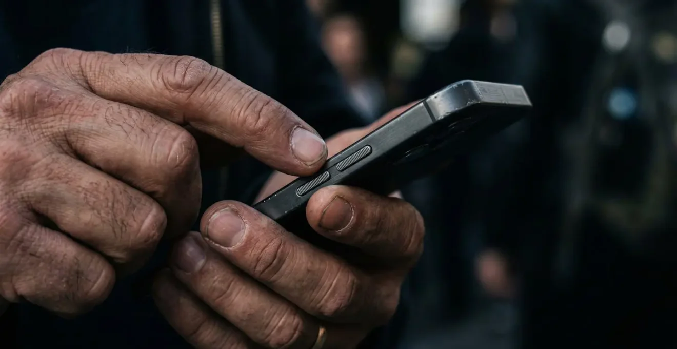 Close-up hands performing smartphone emergency power management in low-light critical situation