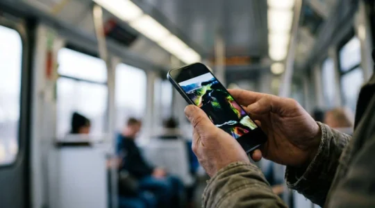 Person watching HDR movie content on smartphone during train commute in changing ambient light conditions