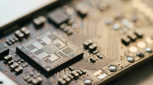 Close-up view of a hardware security module chip embedded on a smartphone circuit board with professional lighting highlighting the secure enclave component