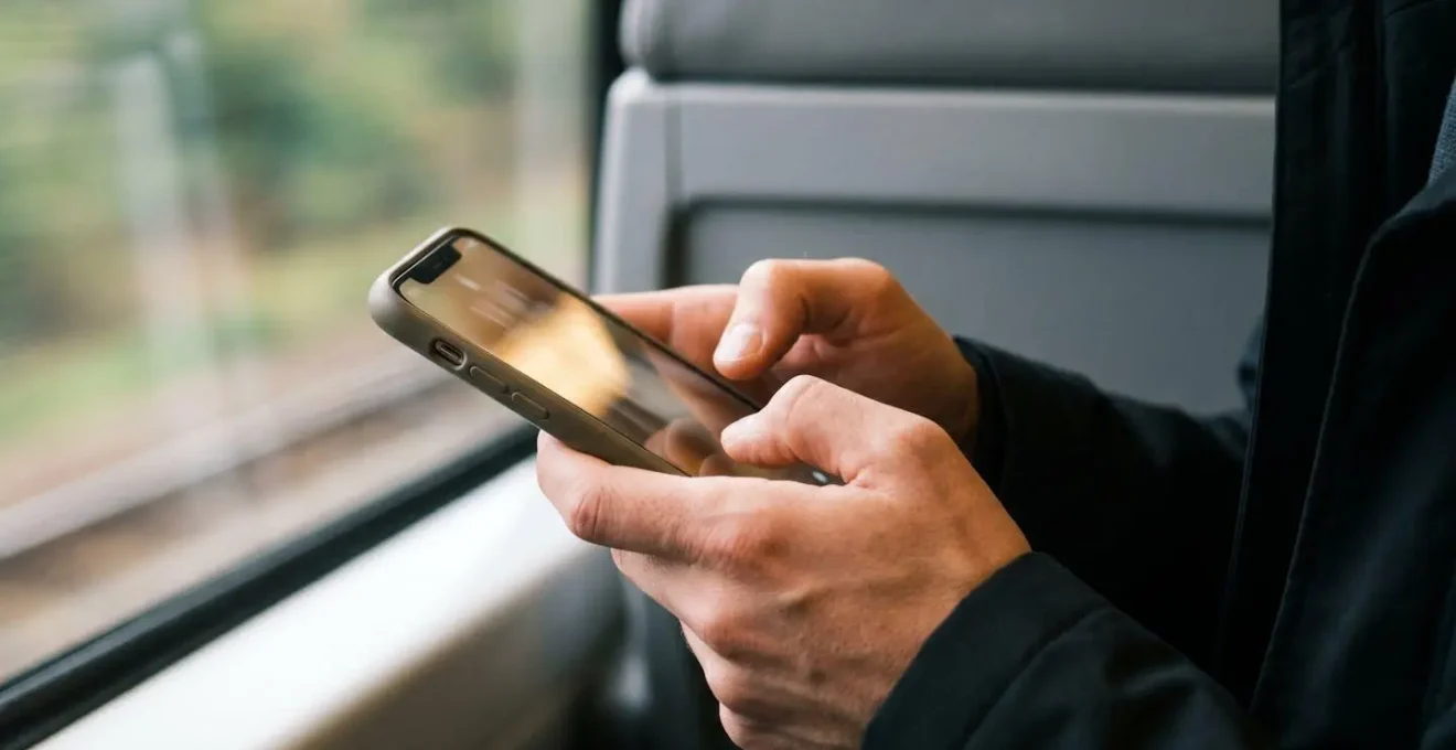 Professional editorial photograph showing hands gripping a smartphone during an intense mobile gaming session with focused attention and natural lighting