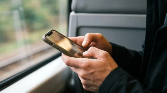 Professional editorial photograph showing hands gripping a smartphone during an intense mobile gaming session with focused attention and natural lighting