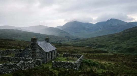 Highland stone cottage beneath misty mountain peaks with radio tower in distance